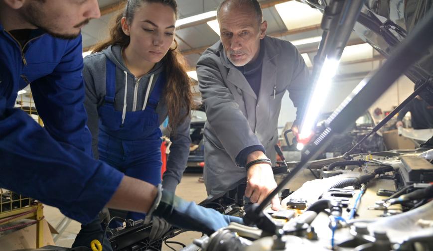 Instructor with students working on engine