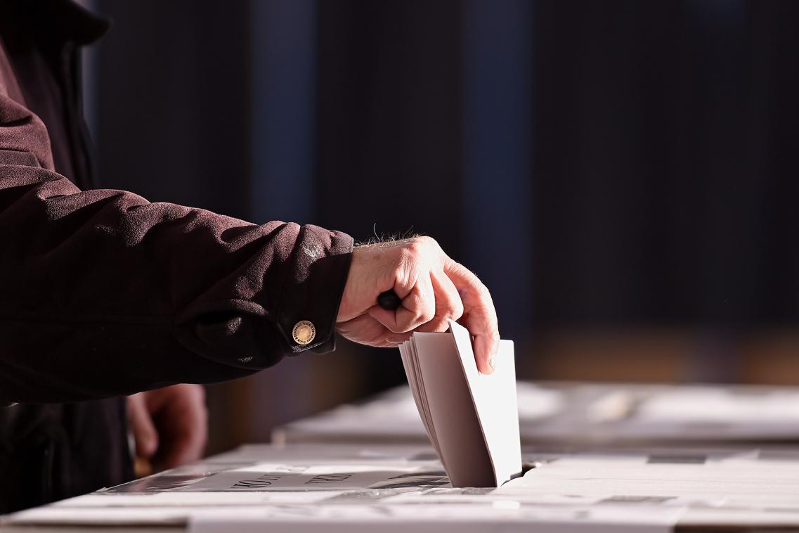 Older man puts voting card in a ballot box