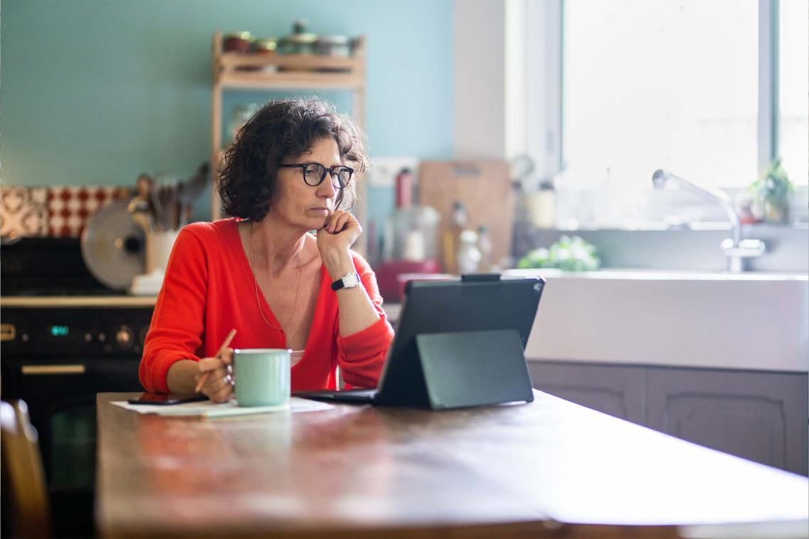 Woman sitting in a kitchen at a laptop