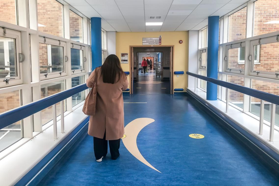 Woman walking down a hospital corridor