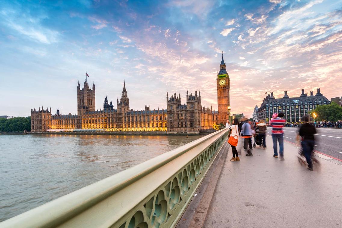 People walking across Westminster bridge at sunset