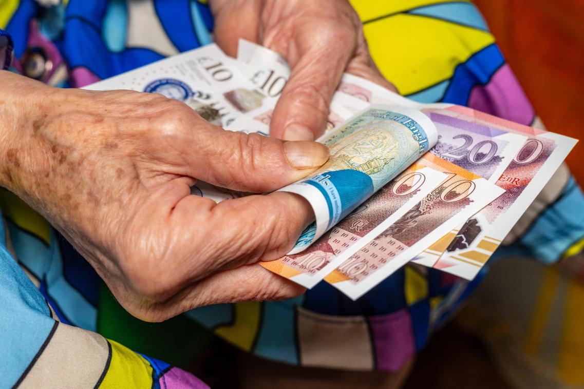 A photo of an older person holding money