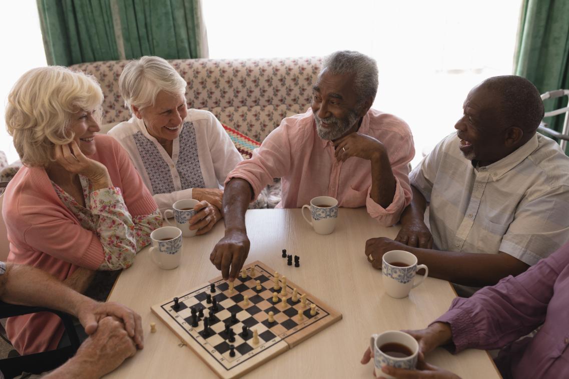 A group of senior people playing chess in a living room