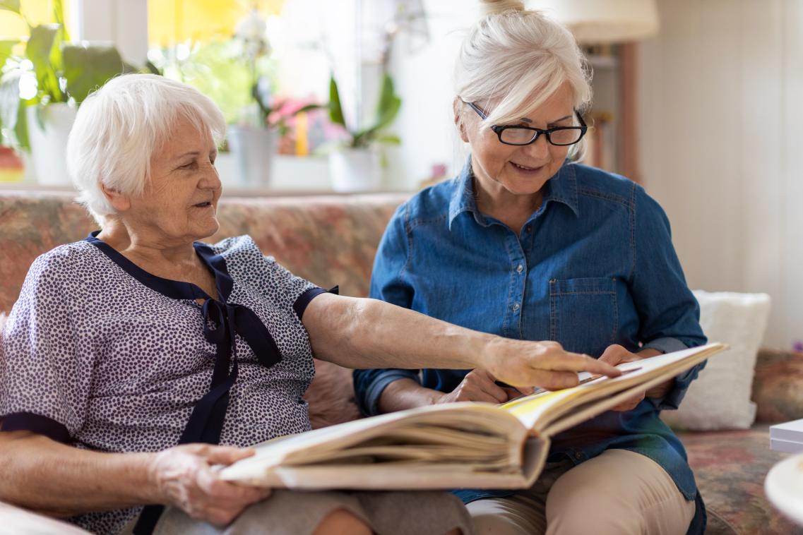 Image of elderly mother and daughter looking through a picture album