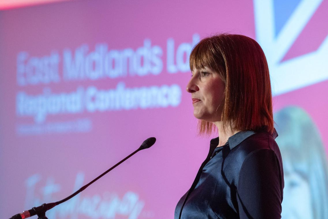 Side profile of Rachel Reeves standing in front of a microphone at a conference 