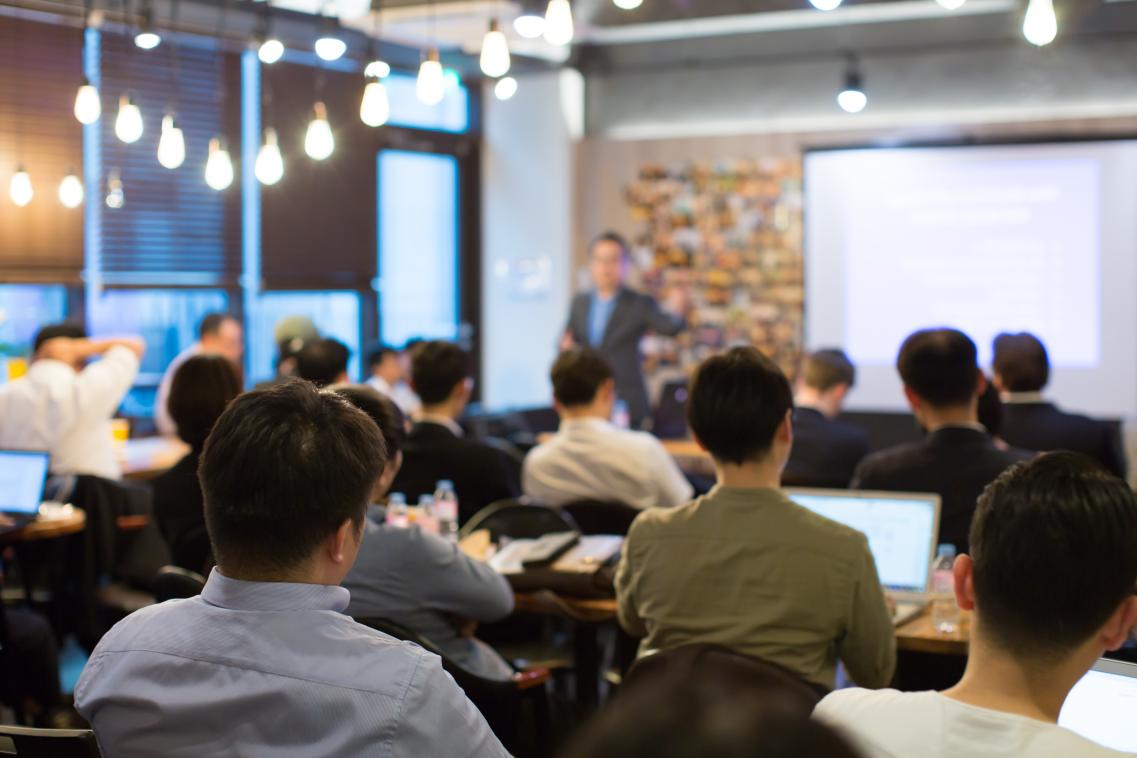 Image from back of the room at a workshop, with speaker presenting to room