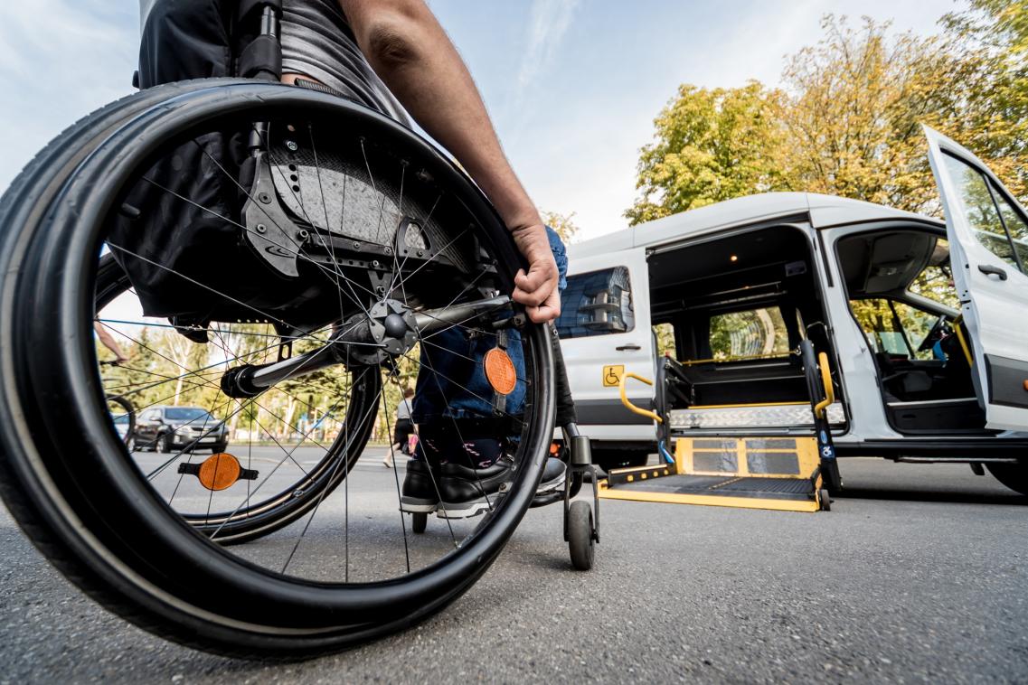 A photo of a person in a wheelchair boarding a minibus