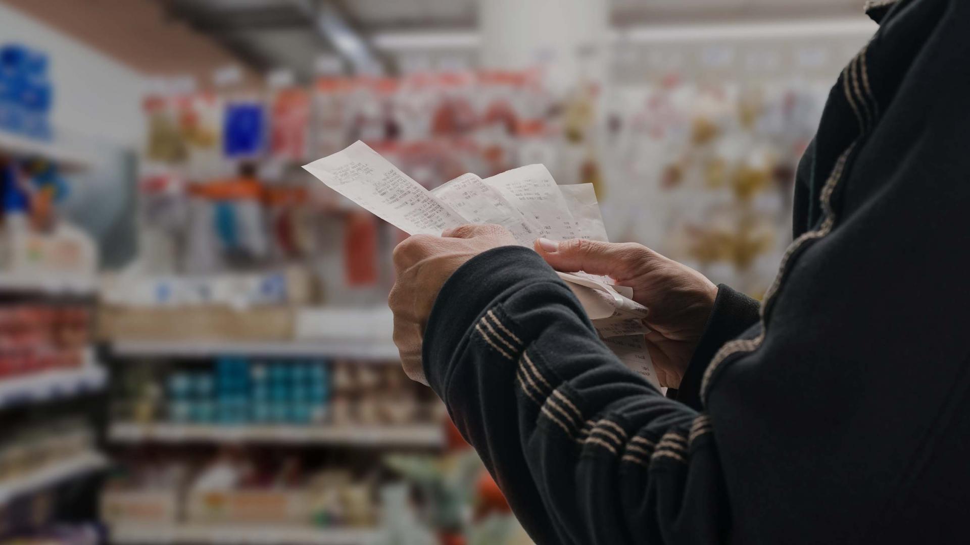 Man holding receipts in a supermarket
