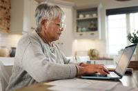 Elderly woman working on laptop for financial planning