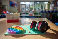 Image of headphones and a fidget toy placed on a classroom table