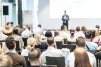 Image of people sitting at a conference facing the stage