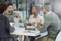 Image of three staff members having a discussion in the office while working together.