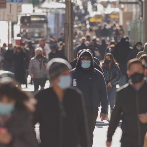 An image of a crowded street with people wearing masks