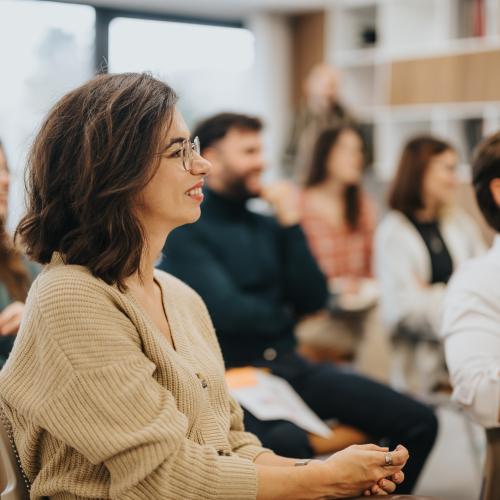 Smiling woman participating in a professional workshop with colleagues in a modern office setting