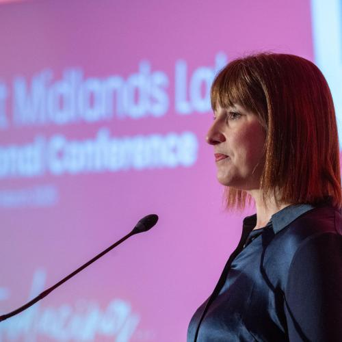 Side profile of Rachel Reeves standing in front of a microphone at a conference 