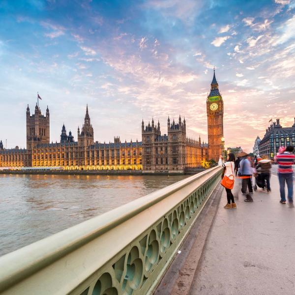 People walking across Westminster bridge at sunset